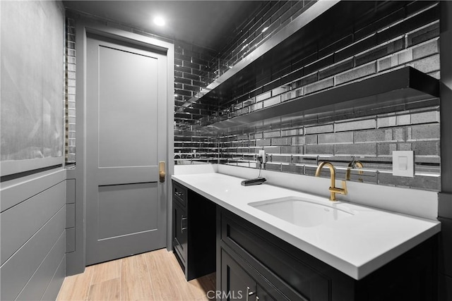 kitchen with light wood-style flooring, dark cabinetry, light countertops, and a sink