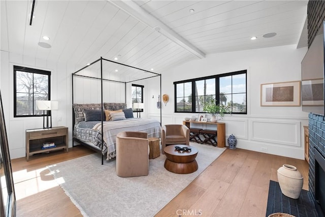 bedroom featuring light wood-type flooring, multiple windows, and a decorative wall