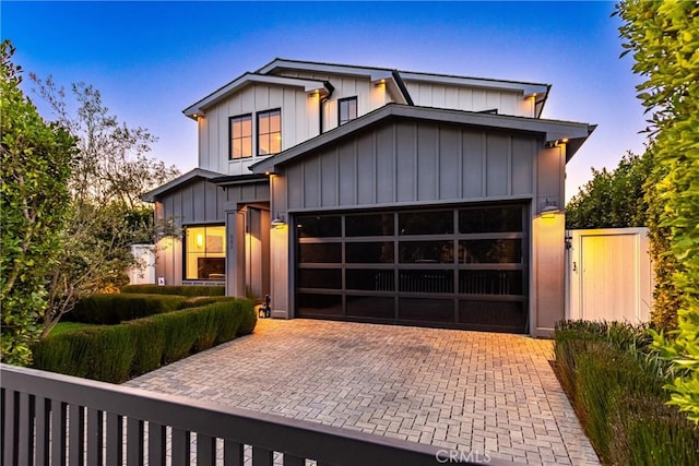 view of front of home featuring a garage, decorative driveway, fence, and board and batten siding