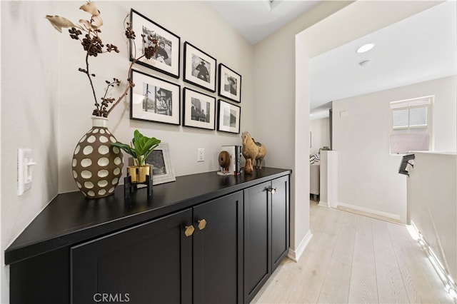 hall with light wood-style floors and baseboards