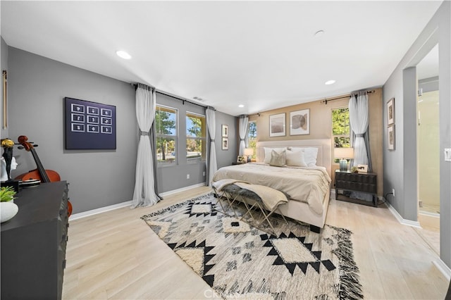 bedroom with light wood-type flooring, multiple windows, and baseboards