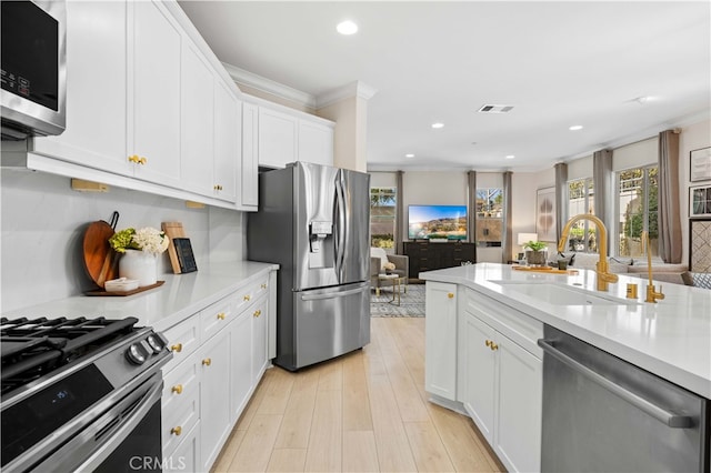 kitchen featuring visible vents, appliances with stainless steel finishes, ornamental molding, light countertops, and a sink