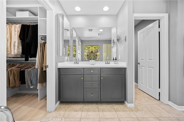 full bathroom featuring double vanity, tile patterned flooring, a sink, and a walk in closet