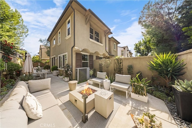 back of house with an outdoor living space with a fire pit, a patio area, fence, and stucco siding