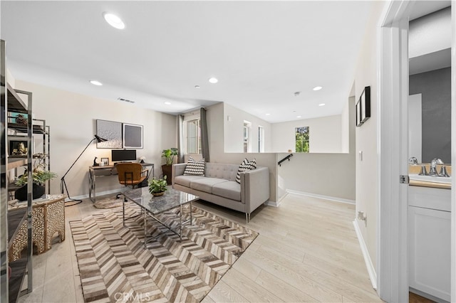 living room with baseboards, light wood finished floors, visible vents, and recessed lighting