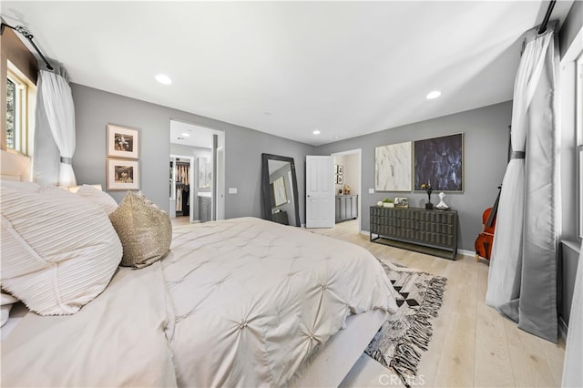 bedroom featuring baseboards, ensuite bath, wood finished floors, and recessed lighting