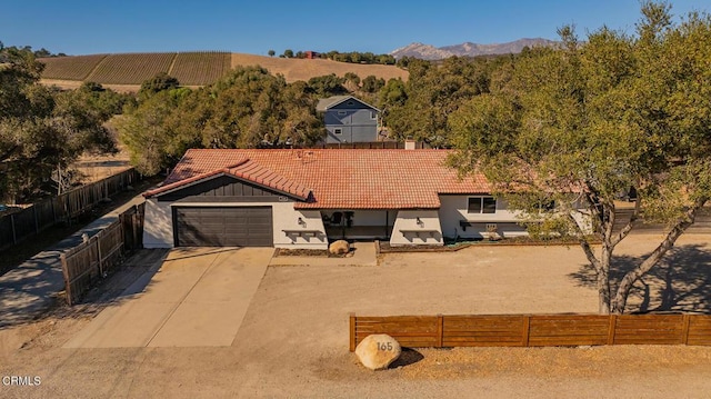 view of front of property featuring fence private yard, a mountain view, a garage, a tile roof, and driveway