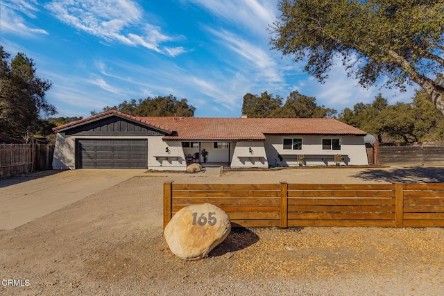 ranch-style home featuring stucco siding, a fenced front yard, concrete driveway, an attached garage, and a tiled roof