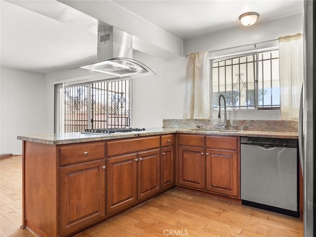 kitchen featuring stainless steel appliances, island range hood, a healthy amount of sunlight, kitchen peninsula, and light wood-type flooring