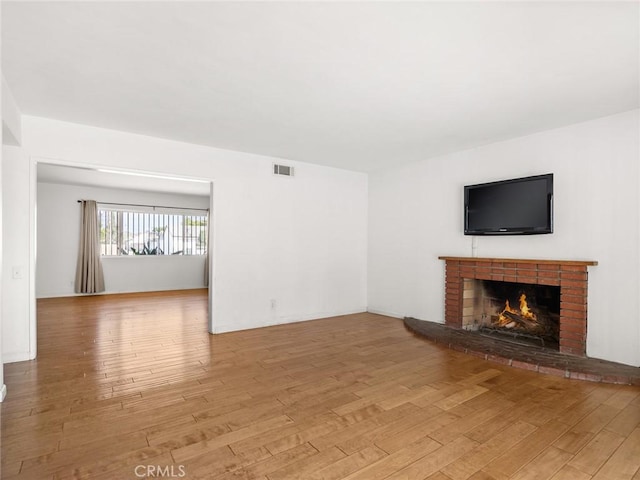 unfurnished living room with a fireplace and light wood-type flooring