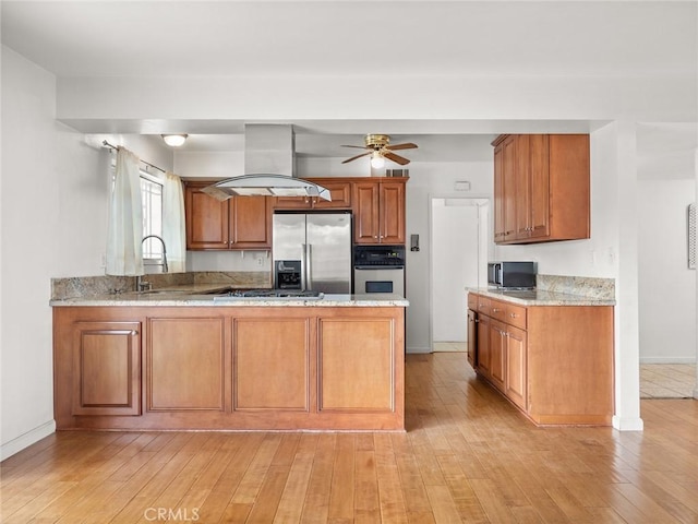 kitchen with sink, light wood-type flooring, kitchen peninsula, island exhaust hood, and stainless steel appliances