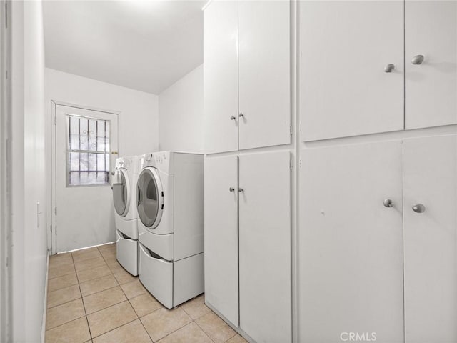 laundry area with cabinets, washer and clothes dryer, and light tile patterned floors