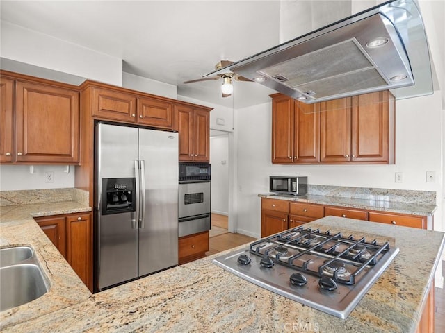 kitchen featuring sink, exhaust hood, light stone counters, ceiling fan, and stainless steel appliances