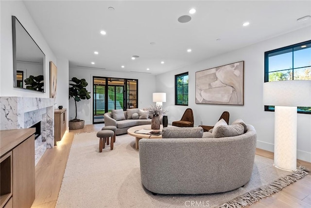 living room featuring light hardwood / wood-style flooring, a wealth of natural light, and a high end fireplace