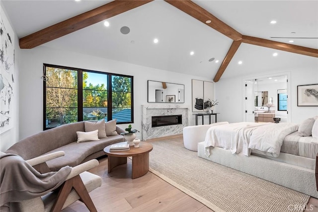 bedroom featuring multiple windows, beam ceiling, a high end fireplace, and light hardwood / wood-style flooring