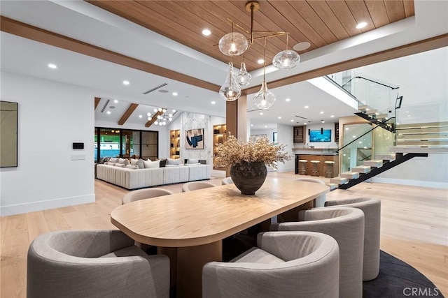 dining space with wood ceiling, beamed ceiling, a raised ceiling, and light wood-type flooring