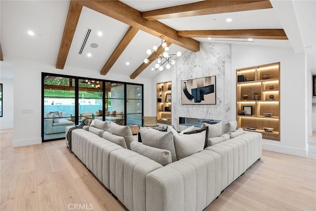 living room with built in shelves, a chandelier, lofted ceiling with beams, light wood-type flooring, and a high end fireplace