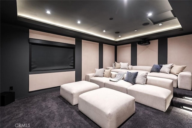 home theater room with dark colored carpet and a tray ceiling