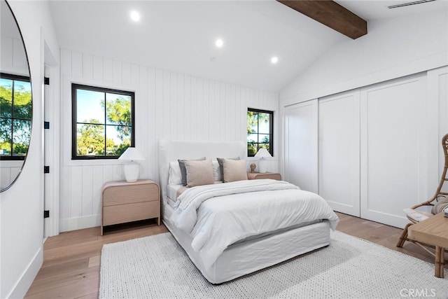 bedroom featuring vaulted ceiling with beams, light hardwood / wood-style floors, and a closet