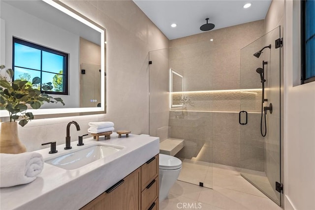 bathroom featuring tile patterned floors, toilet, tile walls, vanity, and a shower with door