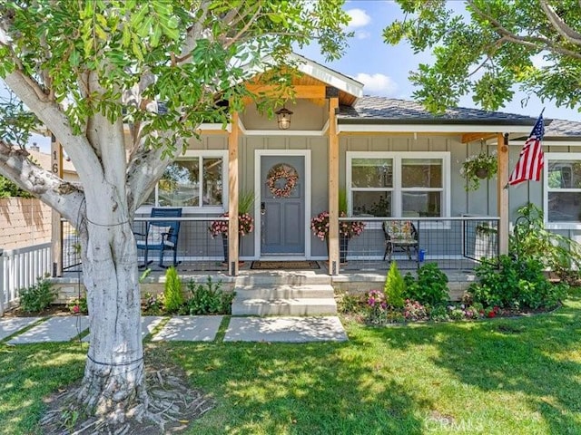 view of exterior entry with a lawn and covered porch