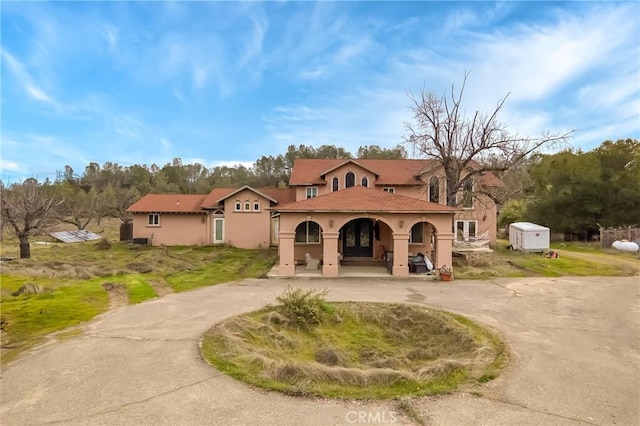 mediterranean / spanish home featuring curved driveway, a storage unit, an outbuilding, and stucco siding