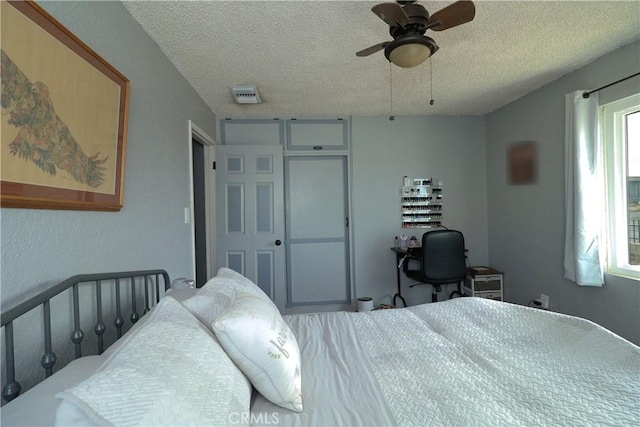 bedroom with a textured ceiling, a closet, visible vents, and a ceiling fan