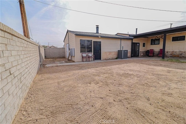 back of house with a fenced backyard, central AC, and a patio