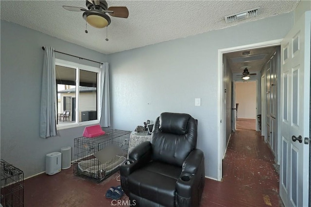 sitting room featuring visible vents, ceiling fan, and a textured ceiling