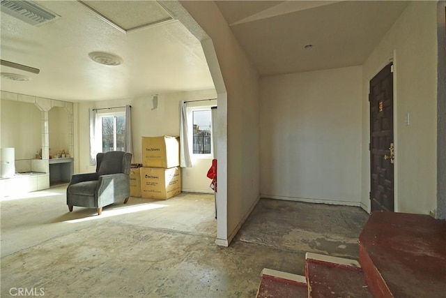 interior space with arched walkways, visible vents, and unfinished concrete floors