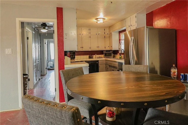 kitchen with a ceiling fan, white cabinets, black dishwasher, light countertops, and freestanding refrigerator