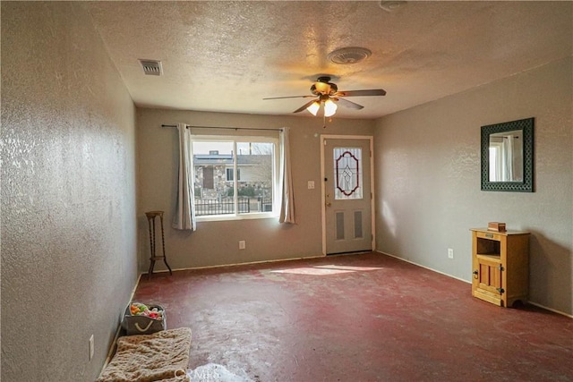 foyer with a textured ceiling, a textured wall, visible vents, and a ceiling fan