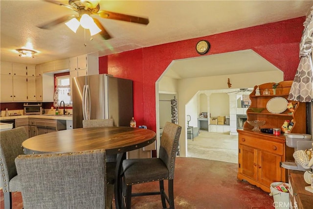 kitchen featuring ceiling fan, a sink, light countertops, freestanding refrigerator, and brown cabinetry