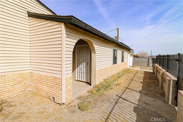 view of property exterior with brick siding and fence