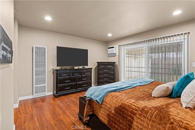 bedroom with a wall mounted air conditioner and wood-type flooring