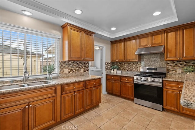 kitchen with a tray ceiling, separate washer and dryer, sink, and stainless steel gas stove