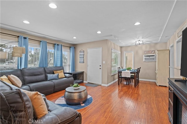 living room featuring a wall unit AC, light hardwood / wood-style floors, and a healthy amount of sunlight