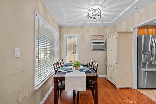 dining area featuring a wall mounted air conditioner, a notable chandelier, and light hardwood / wood-style flooring