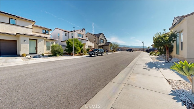 view of street featuring a residential view, curbs, sidewalks, and street lights