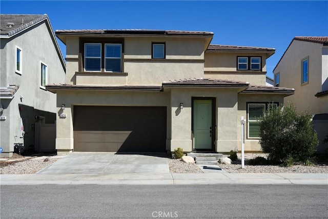 prairie-style house with a garage, concrete driveway, a tiled roof, and stucco siding