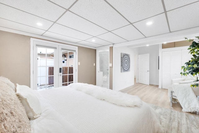 bedroom with french doors, a paneled ceiling, and light wood-type flooring