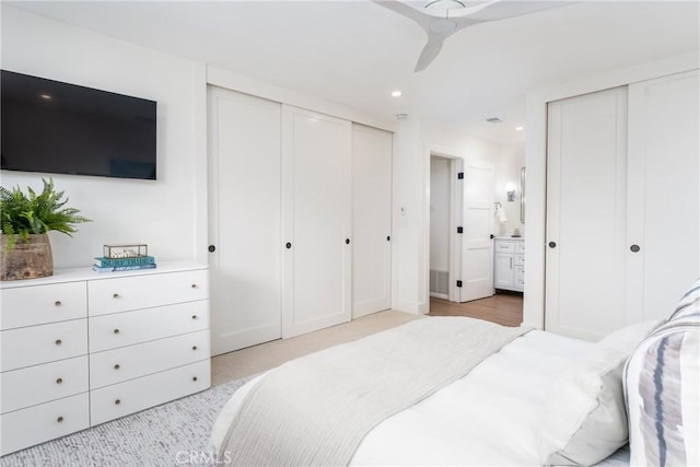 bedroom featuring multiple closets, ceiling fan, and ensuite bathroom