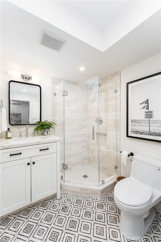 bathroom featuring vanity, toilet, and a shower with door