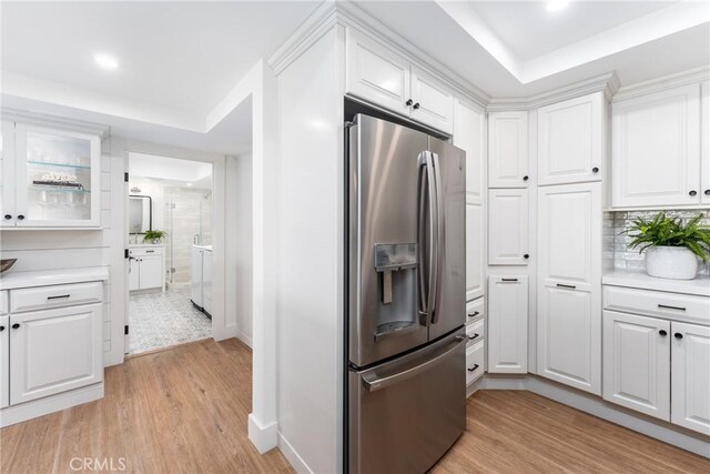 kitchen featuring white cabinetry, stainless steel fridge, light hardwood / wood-style floors, and a raised ceiling