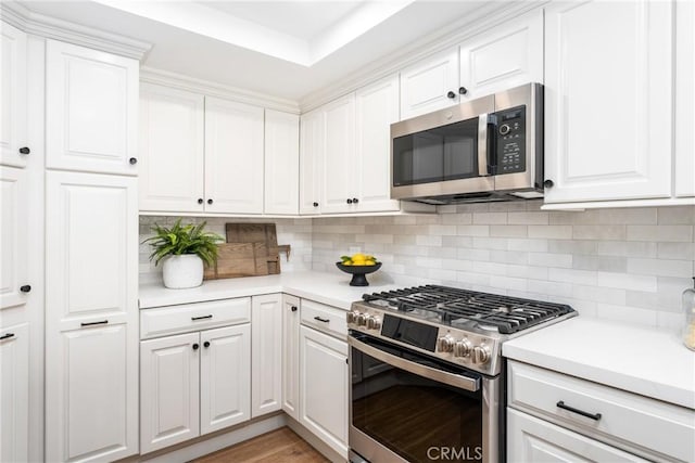 kitchen with white cabinetry, tasteful backsplash, stainless steel appliances, and light hardwood / wood-style flooring