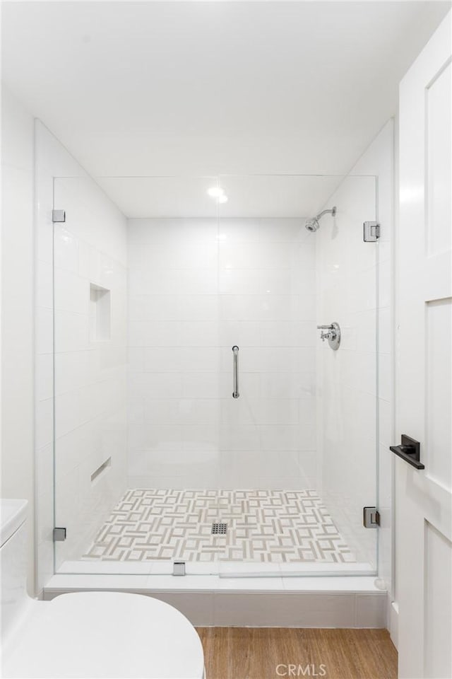 bathroom featuring toilet, hardwood / wood-style floors, and a shower with shower door