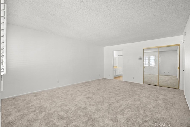 unfurnished bedroom featuring carpet, a closet, a textured ceiling, and ensuite bathroom