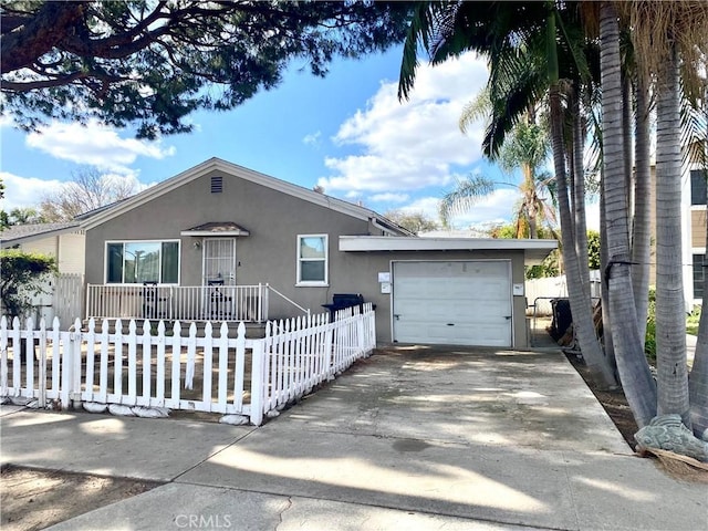 ranch-style home with driveway, a fenced front yard, a garage, and stucco siding