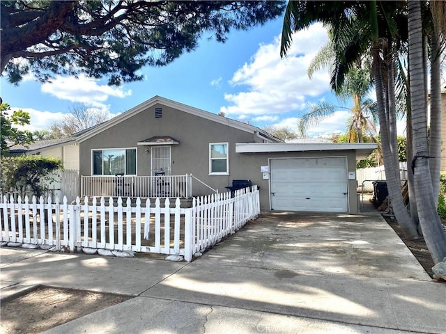 ranch-style house featuring a garage, a fenced front yard, concrete driveway, and stucco siding