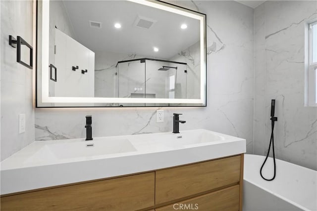 bathroom with an enclosed shower, vanity, tasteful backsplash, and tile walls